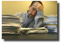 man at desk with piles of documents